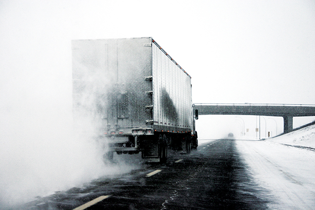 Truck and trailer heading down snow-covered highway